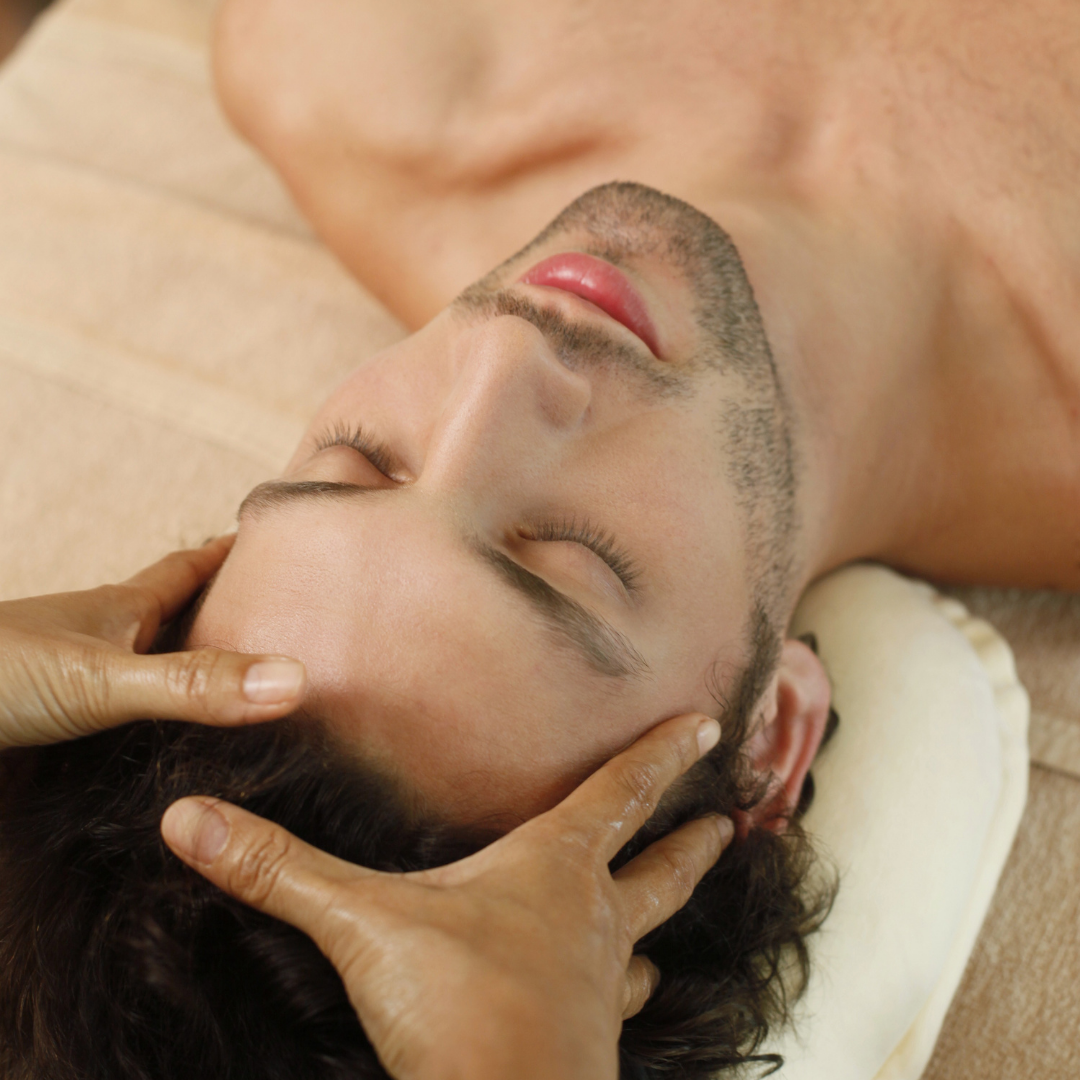 Mains posée sur visage d'un homme pour effectuer un massage de la tête