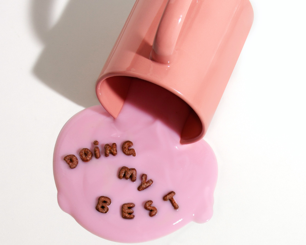 Image d'une tasse rose renversée, dans le liquide versé il est écrit : Doing my best.